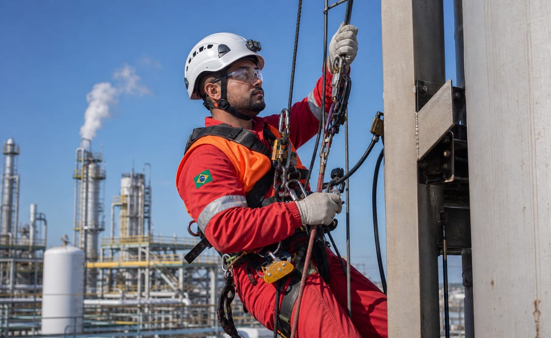 Técnico IRATA suspenso em corda fazendo manutenção em planta petroquímica